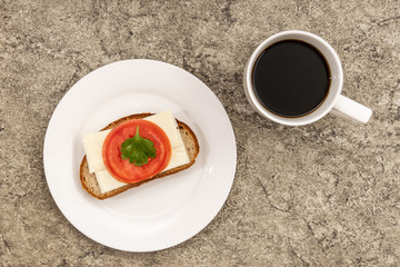 Bread with cheese and tomato. Near a cup of coffee.