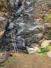 A ladder standing against a almost dry waterfall