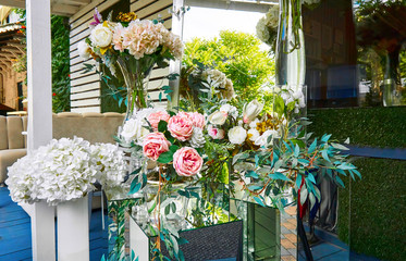 Fototapeta na wymiar Bouquets of white, pink, coral, cream flowers on the background of a wooden house. The concept of floral decoration for holiday, party, feast