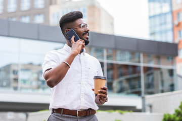 Indian man talking on mobile phone and drinking coffee