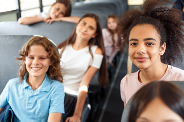 Classmates going to school by bus sitting smiling happy blurred background