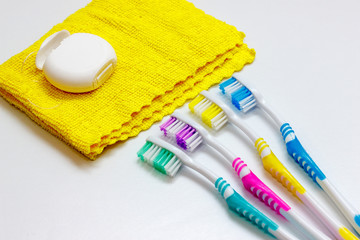 Four multicolored toothbrushes and dental floss over white background