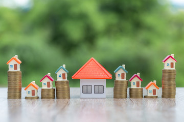Orange roof house Held by investors Will put on a pile of coins.Concept of planning for saving money to buy a house, mortgage concept and investment Saving or investing for the house.