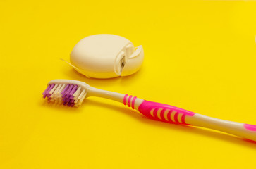 Pink toothbrushes and dental floss . Yellow background. Space for text