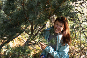 Girl in the autumn forest among coniferous branches.