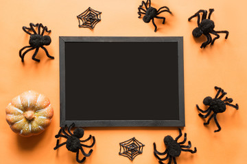 Halloween holiday blank with party decor, black spiders, web on orange. Flat lay, top view. Space for text
