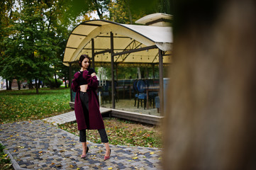 A tall leggy young beautiful and elegant model woman at claret coat.