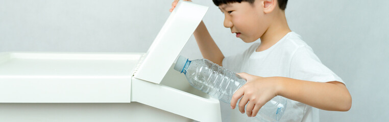 A kindergarten boy learning to sorted plastic water bottles into the recycle bin separated from others. Waste segregation, Single-use plastic problems, Environmental awareness, Zero waste concept.