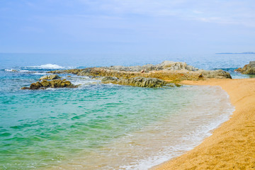Sand beach with rocks in cloudy weather in Lloret de Mar, Costa Brava, Spain. Concept of rest.