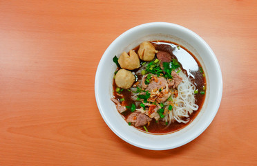 Thai stlye noodle blood soup serve with pork ball and vegetable topping with fried galic on a white bowl in Thailand call 