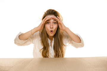 Young sad woman opening the biggest postal package isolated on white. Shocked upset female model on top of cardboard box looking inside. Gift, present, delivery, shipment, sales, black friday concept.