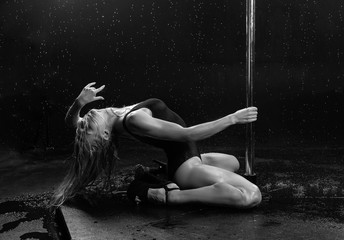 Beautiful wet athletic busty elegant blonde girl performs artistic elements of an exotic dance on the rain. Health, lifestyle, sports, black white monochrome design. Copy space.