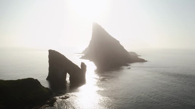 Aerial drone video flying over Drangarnir and Tindholmur sea stacks in Atlantic ocean, Faroe Islands. UHD 4k footage