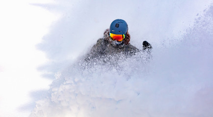 female snowboarder curved and brakes spraying loose deep snow on the freeride slope. downhill with snowboards in fresh snow. freeride world champion.