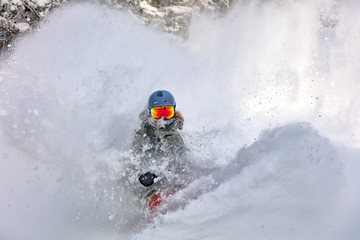 female snowboarder curved and brakes spraying loose deep snow on the freeride slope. downhill with snowboards in fresh snow. freeride world champion.