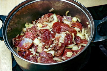 Pan with pieces of marinated meat with onions and spices. Top view
