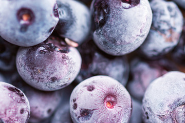 Heap of frozen blueberries of violet color with beautiful frost pattern and texture. Superfoods...