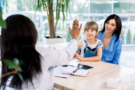 Happy Caucasian Child Little Girl Give High Five To African Woman Pediatrician Welcome Little Patient And Mom At Consultation, Trusting Kid With Doctor. Medical Health Care Treatment Result