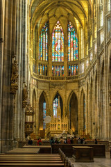 Fototapeta premium Tourists inside Vitus Cathedral near the altar with mosaic on glass window