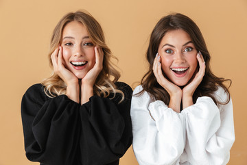 Portrait of two joyful women smiling while propping their heads