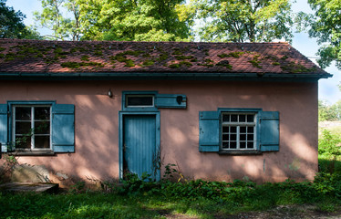 Fototapeta na wymiar abandoned old house with blue door in shadow of trees