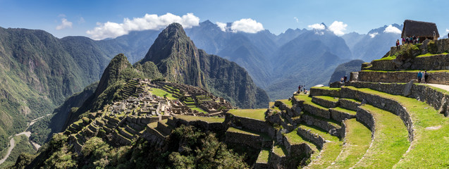Panoramic view of Machu Picchu ruins in Peru. Behind we can appreciate big and beautiful mountains full of green vegetation. Archaeological site, UNESCO World Heritage - obrazy, fototapety, plakaty