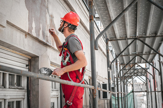 Construction mason worker plastering building wall using cement plaster mix