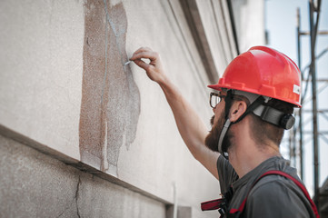 Man worker standing on scaffolding and restore old building facade
