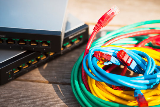Home office concept.  Black and silver cloud switches interconnected using bright cables on the wooden background. Smart home equipment. Space for your text. Closeup.