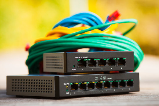 Home office concept.  Black and silver cloud switches interconnected using bright cables on the wooden background. Smart home equipment. Space for your text. Closeup.