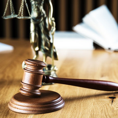 Law and Justice concept. Mallet of the judge, books, scales of justice. Gray stone background, reflections on the floor, place for typography. Courtroom theme.