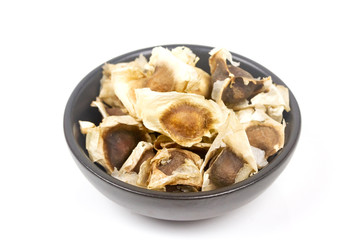 Close up moringa oleifera seeds in black bowl ceramic isolated on white background.