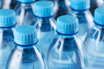 Rows of plastic bottles. Necks of plastic bottles with still water with blue caps, close up