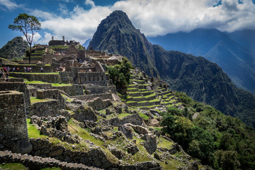 Machu Picchu city from the inside. Huayna Picchu mountain and green vegetation can be seen. Cloudy day. Archaeological site, UNESCO World Heritage, Peru.