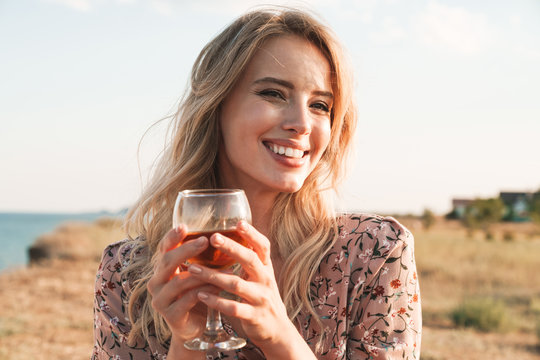 Photo of cheerful blonde woman holding wine glass and smiling