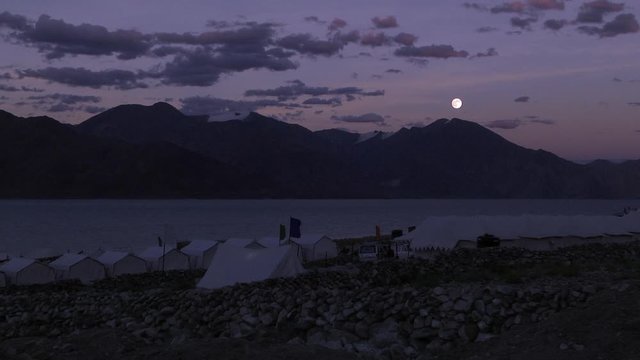 Surreal view of Himalayan landscape near a camp hotel lit up by a full moon and a purple twilight sky at Ladakh India.