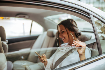 Cheerful business woman on the backseat of a car, copy space.
