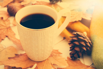 Autumn composition concept background. Dark coffee cup, with autumn bright leaves, pine cones on white rustic background