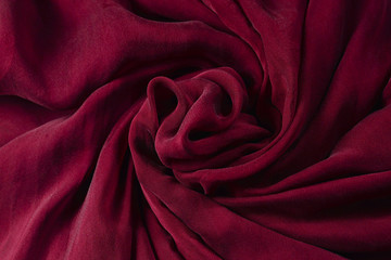 Soft smooth burgundy silk fabric background. Fabric texture.