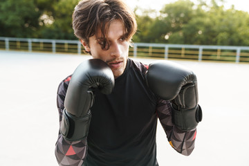 Photo of handsome caucasian man doing workout in boxing gloves