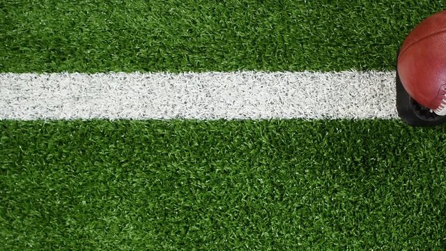 Overhead slider view of a yard line and an American football on a kicking tee