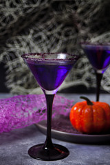 Two glasses with purple cocktail for Halloween party on the dark background