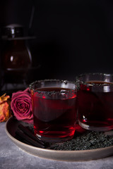 Two glasses with red cocktail, dried roses for Halloween party on the dark background