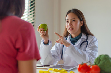 friendly nutritionist female doctor medical talking about diet plan with green apple and vegetable to young patient woman in office hospital, nutrition, food science, nutritional, healthy food concept