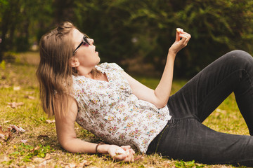 Young woman lying down on the grass while holding garlic clove in one hand