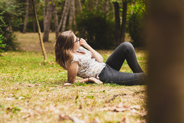 Naklejka na ściany i meble Young woman relaxing on the green grass in the park
