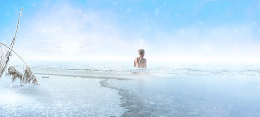 Woman goes into a frozen lake for ice swimming in winter