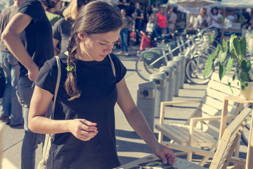 Female customer reading leaflet at outdoor market.