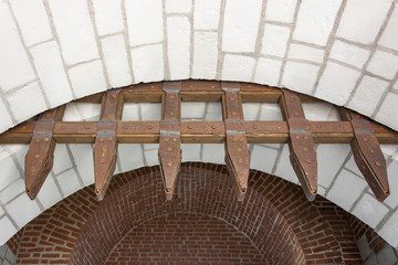 An ancient gateway made of stonework, wood and metal. Rusty and weathered.