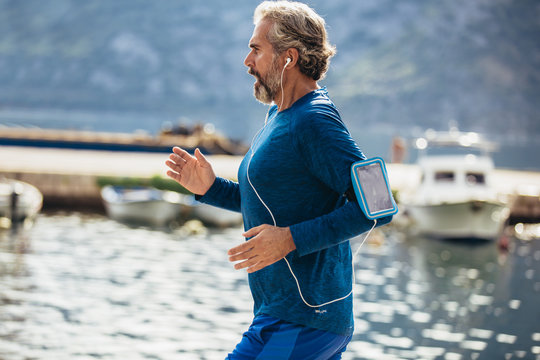 Active senior man jogging on the pier on a sunny day